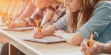 the picture shows students writing on a piece of paper